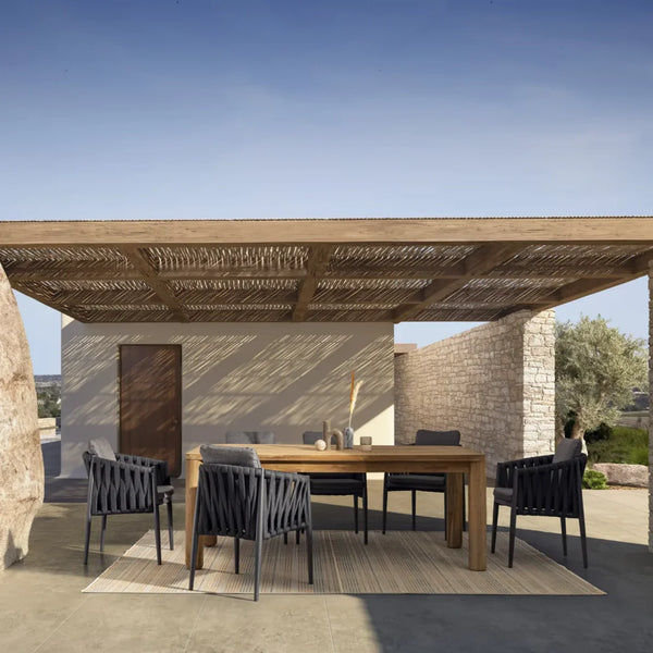 Outdoor-Essgruppe mit Holztisch und schwarzen Stühlen unter Pergola im mediterranen Ambiente