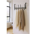 Haku Türgarderobe in Schwarz mit 5 Haken, daran hängen beige und braune Fransentücher an weisser Wand