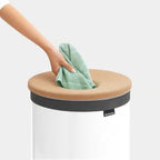 Brabantia Wäschekorb 60L Weiß mit Korkdeckel – Hand legt grünes Tuch hinein