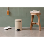 Brabantia Treteimer New Icon 3L in Soft Beige im Badezimmer neben Holzhocker mit gefalteten Handtüchern