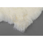 Weißes Lammfell Teppich von KARE – flauschig & naturbelassen auf grauem Untergrund
