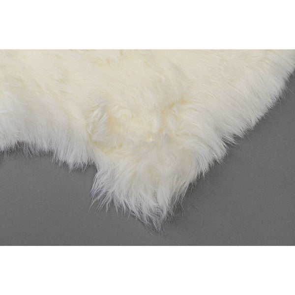 Weißes Lammfell Teppich von KARE – flauschig & naturbelassen auf grauem Untergrund