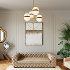 Abstraktes Wandbild in Weiß-Gold über einem Chesterfield-Sofa in elegantem Wohnzimmer