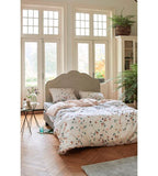Cremefarbenes Bettwäsche-Set mit Schmetterlings-Muster auf elegantem Bett in hellem Schlafzimmer