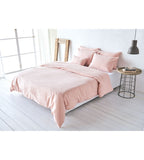 Rosafarbenes Bettwäsche-Set mit Kissenbezügen auf einem weissen Doppelbett in modernem Schlafzimmer