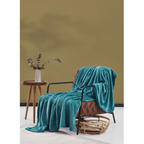 Aquablaue Fleecedecke auf braunem Sessel mit Holztisch und Vase vor ockerfarbener Wand