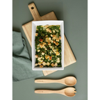 Weiße Gratinform mit Spinat und Croutons auf Holzbrett, mit Holzbesteck und grünem Tuch