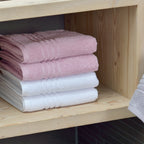 Gefaltete Gästetücher in Rosa und Schneeweiss Leonora im Holzregal – weiche Frotteetücher 30x50 cm