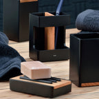 Kela Toilettengarnitur Cube schwarz mit Holzakzenten, Zahnbürstenhalter und Seifenschale auf Holzunterlage
