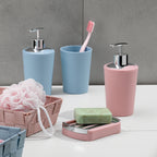 Badezimmer-Set in Rosa und Blau: Seifenspender, Zahnputzbecher, Seifenschale und Korb auf weißem Waschtisch