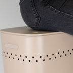Beige Wäschebox Malaga von Kela mit Lochdesign und schwarzer Jeans auf dem Deckel