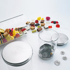 Kela Vorratsdose Baker 0,25L aus Glas mit Edelstahldeckel, befüllt mit Knöpfen, daneben liegende Dose mit Süssigkeiten