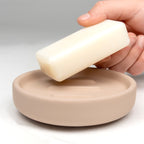 Kela Seifenschale Sana in Beige mit einer Hand, die einen Seifenriegel darüber hält