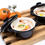 Kela Mini-Auflaufform Malin in Schwarz mit Eierspeise und Speck auf Holzbrett, daneben Tomaten