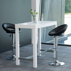 Zwei schwarze drehbare Barhocker mit gepolsterten Sitzen und Chromfüßen um weißen quadratischen Bartisch mit Glasvase vor.