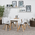 Essgruppe mit weißem Esstisch und vier weißen Stühlen mit hellen Holzbeinen auf grauem Teppich vor weißer Wand mit zwei.
