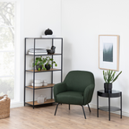 Actona Seaford Bücherregal schwarz mit Holzböden, grüner Sessel und Beistelltisch in modernem Wohnzimmer