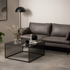 Actona Strington Salontisch schwarz mit Glasplatte und Metallgestell im modernen Wohnzimmer mit grauem Sofa