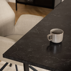 Schwarzer Marmor-Esstisch Actona Amble mit Keramiktasse und cremefarbenen Stühlen im modernen Wohnzimmer