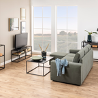 Actona Newton TV-Tisch Schwarz im modernen Wohnzimmer mit grünem Sofa und großem Panoramafenster
