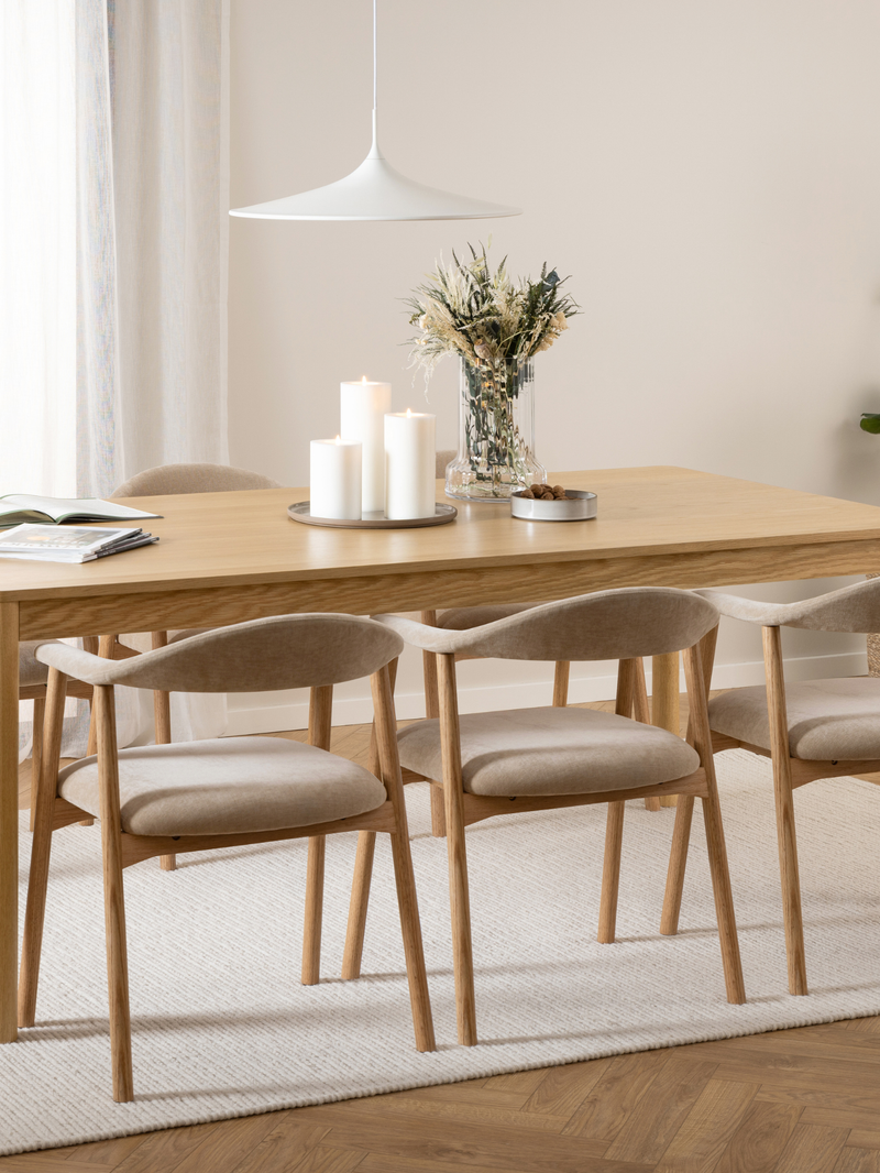 Actona Addi Armlehnenstuhl Beige an hellem Esstisch mit Kerzen und Blumen, skandinavisches Wohndesign