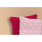 Zwei flauschige Kissen mit Herzmuster in Pink und Dunkelrot von Magma Fluffy vor beigem Hintergrund