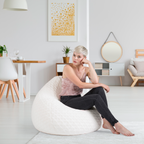 Frau sitzt entspannt auf weißem Magma Sitzsack mit Rautenmuster im modernen Wohnzimmer