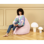 Frau sitzt lächelnd auf rosa Magma Beanbag Sitzsack auf Parkettboden neben weissen Pilzlampen