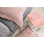 Grauer Sofa mit rosa Cordkissen und Beistelltisch mit Buch „The Monocle Guide to Cosy Homes"