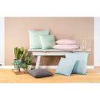 Magma Riva Dekokissen in Mint, Rosa und Blau auf weisser Holzbank mit Kakteen und Glaskaraffe