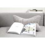 Magma Shara Leseknochen-Kissen in Grau auf grauem Sofa mit aufgeschlagenem Buch