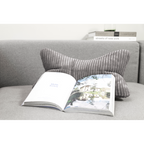 Graues Leseknochen-Kissen Shara auf hellgrauem Sofa mit aufgeschlagenem Buch – gemütliches Wohnzimmer-Accessoire