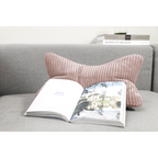 Magma Shara Leseknochen-Kissen in Rosa auf grauem Sofa mit aufgeschlagenem Buch – gemütliches Wohnzimmer-Accessoire