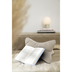 Beige Cord-Buchstütze mit Katzenohren auf Sofa, offenes Buch, Kugellampe im Hintergrund