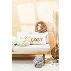 Gemütliche Sitzbank aus Holz mit Schaf-Kissen, Igel-Plüschtier und "Cosy"-Kissen in Naturtönen