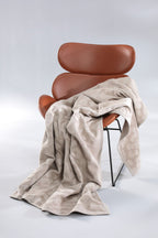Biederlack Kuscheldecke Feel Leo in Beige auf cognacfarbenem Ledersessel mit Metallgestell