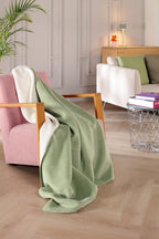 Biederlack Kuscheldecke Doubleface in Mint/Weiss auf rosafarbenem Sessel im modernen Wohnzimmer