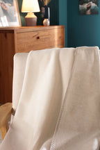 Biederlack Kuscheldecke Doubleface in Ecru/Feder über Sessel drapiert, gemütliches Wohnzimmer