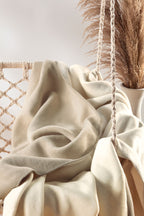 Biederlack Kuscheldecke Doubleface in Ecru/Feder auf Makramee-Hängesessel mit Pampasgras-Dekoration