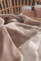 Biederlack Kuscheldecke Soft Cosy in Woodrose auf Sessel mit rosa Tassen im Hintergrund