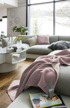 Biederlack Kuscheldecke Doubleface in Rosa/Pergament auf grauem Sofa im modernen Wohnzimmer