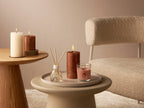 Bolsius Geschenkset Cozy Hideaway Apple Cinnamon: Kerzen und Diffuser auf Beistelltischen neben Sessel