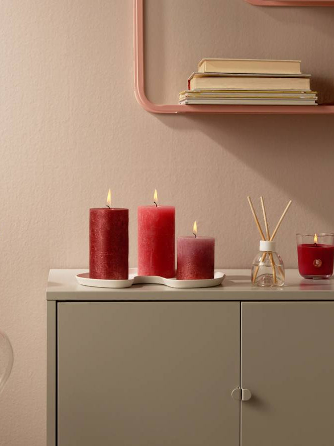 Bolsius Geschenkset Fruit Splash Granatapfel: 3 rote Duftkerzen und Reed Diffuser auf grauem Sideboard