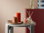 Bolsius Geschenkset Juicy Bliss Peach: Duftkerzen und Reed Diffuser auf grauem Beistelltisch