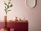 Bolsius True Scents Duftkerzen Magnolie in rosa Gläsern mit Reed Diffuser auf Holzbrett