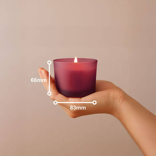Bolsius True Joy Duftkerze im Glas, Vanille, Bordeauxrot, 83x66mm, in einer Hand gehalten, brennende Flamme