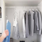 Weisse Holzkleiderbügel mit Jacken und Hemden in grau in einem modernen weissen Kleiderschrank