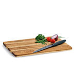 Zeller Schneidebrett aus Holz mit Küchenmesser, Tomaten, roter Zwiebel und Kräutern auf weißem Hintergrund