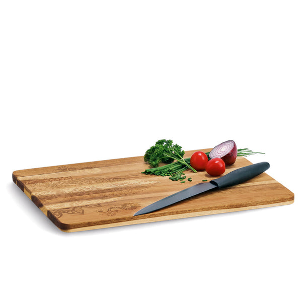 Zeller Schneidebrett aus Holz mit Küchenmesser, Tomaten, roter Zwiebel und Kräutern auf weißem Hintergrund