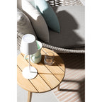 Bizzotto LED Tischlampe Etna in Weiss auf rundem Holztisch neben mintfarbener Tasse und Glas, Outdoor-Lounge